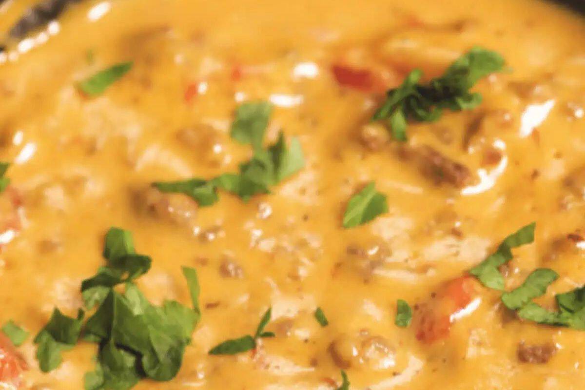 A close-up of creamy cheeseburger dip with ground meat, diced tomatoes, and fresh cilantro garnish—perfect for your Memorial Day or Labor Day patriotic party foods spread.