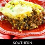 A slice of Southern chili pie with a golden cornbread crust sits on a red plate, revealing a hearty filling of chili, beans, and ground meat.
