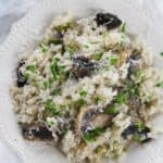 A white plate with Creamy dish garnished with grated cheese and chopped parsley.