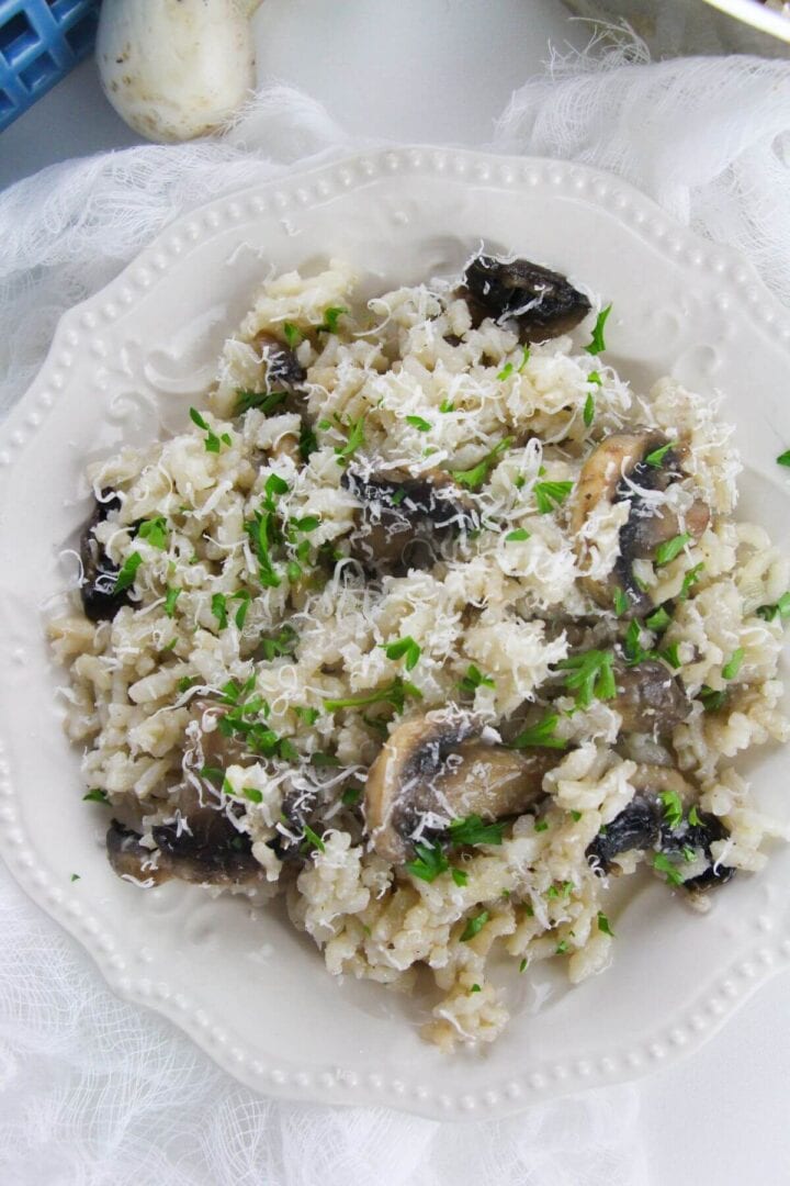 A white plate with Creamy dish garnished with grated cheese and chopped parsley.