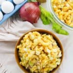 A bowl of the side celery, and red onion sits beside a tray of eggs, a whole red onion, celery stalks.