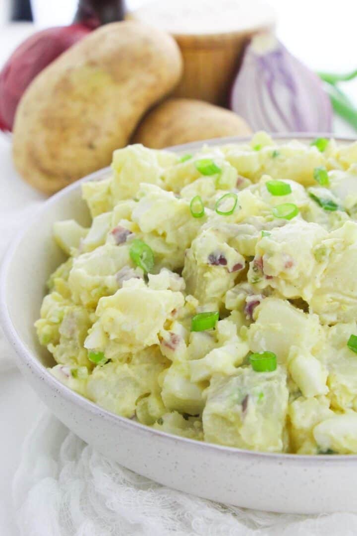 A white bowl of the dish with the vegetables in the background.