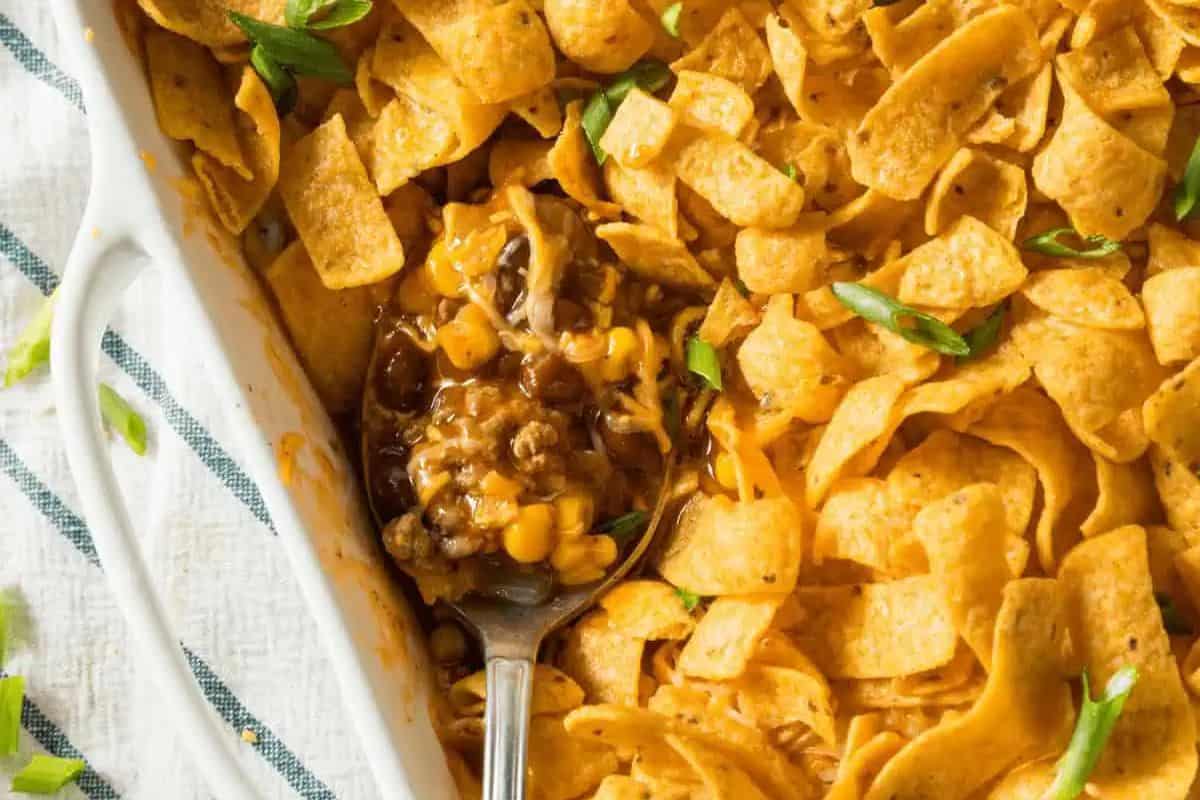 Perfect for Memorial Day or Labor Day, this casserole dish is loaded with Fritos chips, melted cheese, ground meat, beans, and corn—topped with green onions—for a crowd-pleasing patriotic party food.