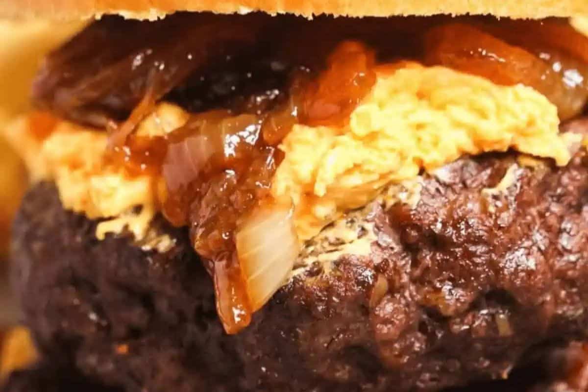 Close-up of a hamburger featuring a beef patty, caramelized onions, melted cheese, and a bun—perfect for serving at your next Memorial Day cookout or as part of your favorite patriotic party foods.
