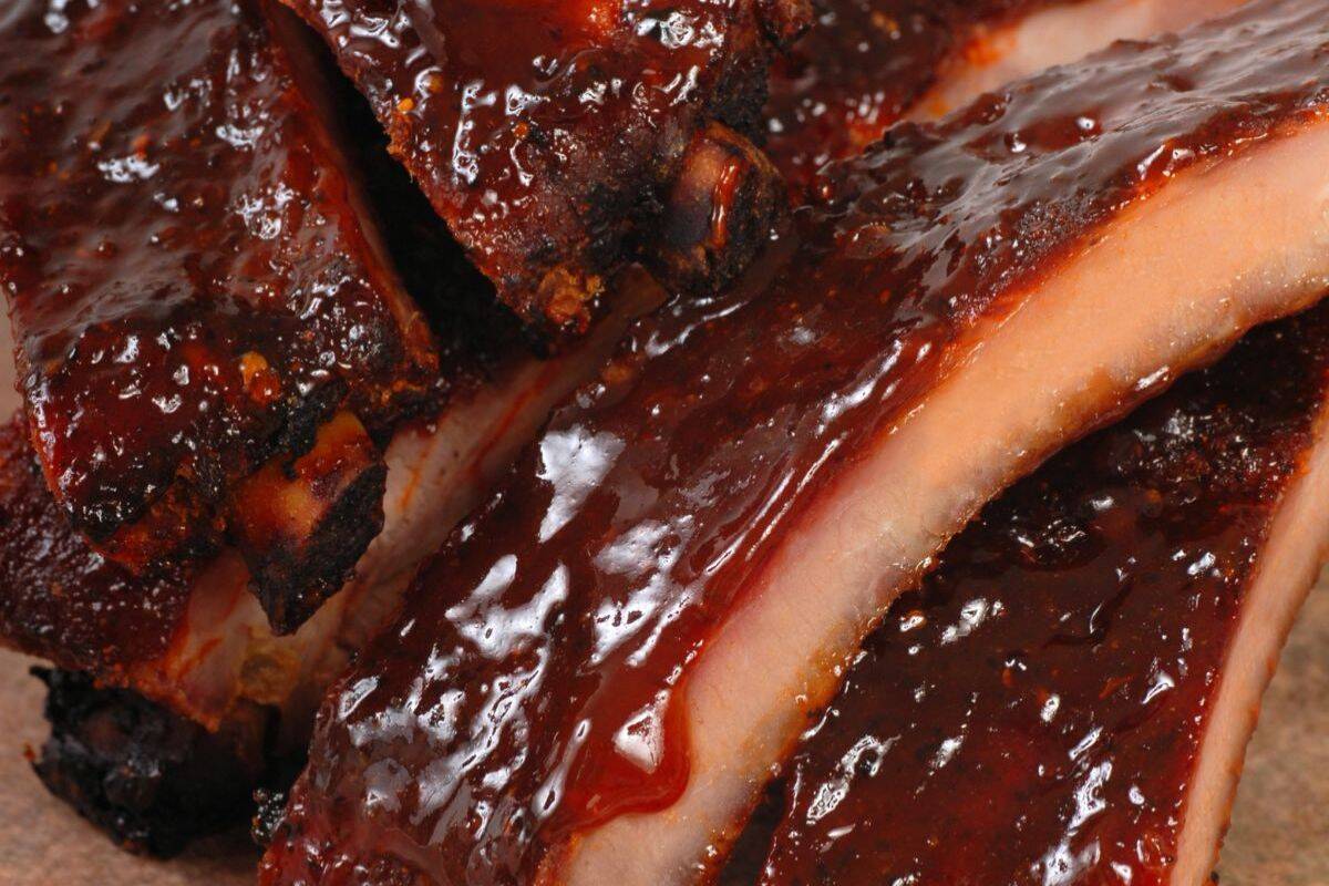 Close-up of glazed, barbecued pork ribs with a glossy sauce coating and visible char marks on the meat—a mouthwatering classic from our All American recipes collection.