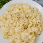 A plate of the dish garnished with ground black pepper, served on a white plate with parsley and a fork in the background.