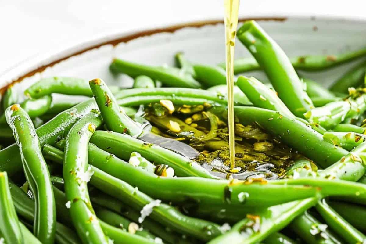 This image captures tender green beans being drizzled with a flavorful Italian vinaigrette. Infused with herbs, garlic, and olive oil, the marinade gives the beans a zesty, tangy flair. It’s a chilled side dish that’s as refreshing as it is bold.