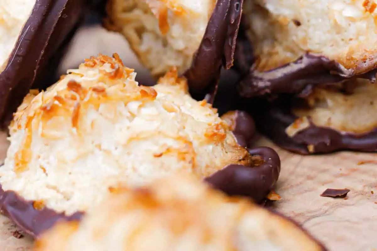 Close-up of coconut macaroons dipped in chocolate, resting on parchment paper—a delightful coconut dessert for anyone who loves irresistible coconut recipes.