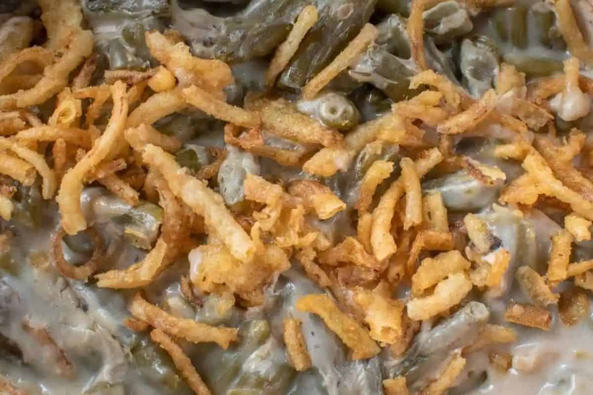 Creamy and comforting, this slow cooker version of green bean casserole is loaded with tender beans and topped with crunchy fried onions. The close-up shot captures the savory sauce and crispy topping in all its glory. A no-hassle, classic dish perfect for holiday meals.