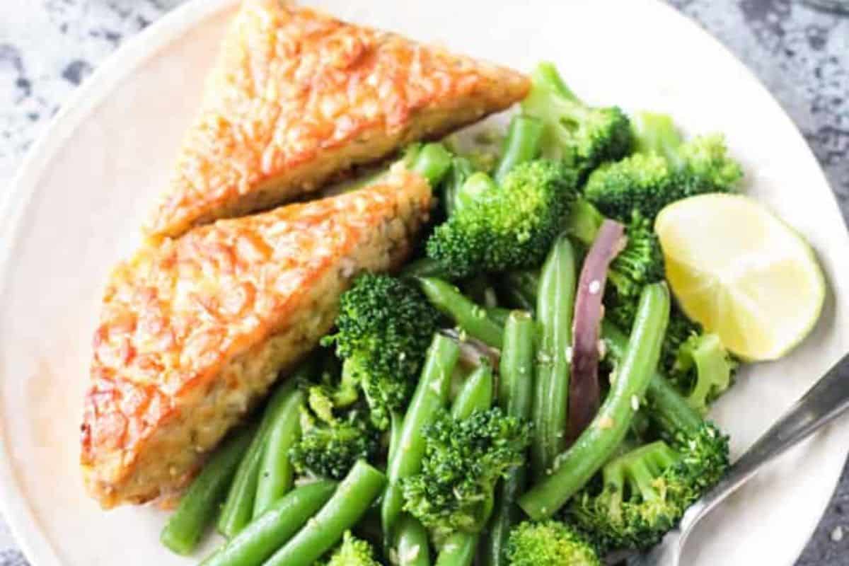 This colorful stir fry features crisp-tender green beans and broccoli, tossed with red onion slivers and sesame seeds. Served with golden triangles of tempeh and a lime wedge, it’s a healthy, plant-powered plate. Light, vibrant, and full of texture.