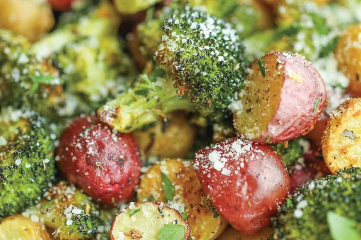 Close-up of delicious roasted broccoli and halved red potatoes topped with grated parmesan cheese and herbs—a perfect addition to your favorite broccoli recipes, even for picky eaters.