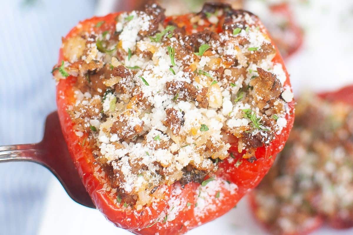 Close-up of a red bell pepper stuffed with rice and ground beef, served on a silver spoon.