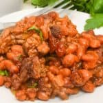 Ground beef and baked beans on a white plate.