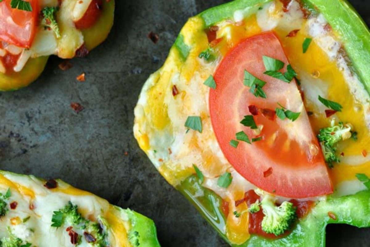 Close-up of a green bell pepper slice with pizza toppings on top.