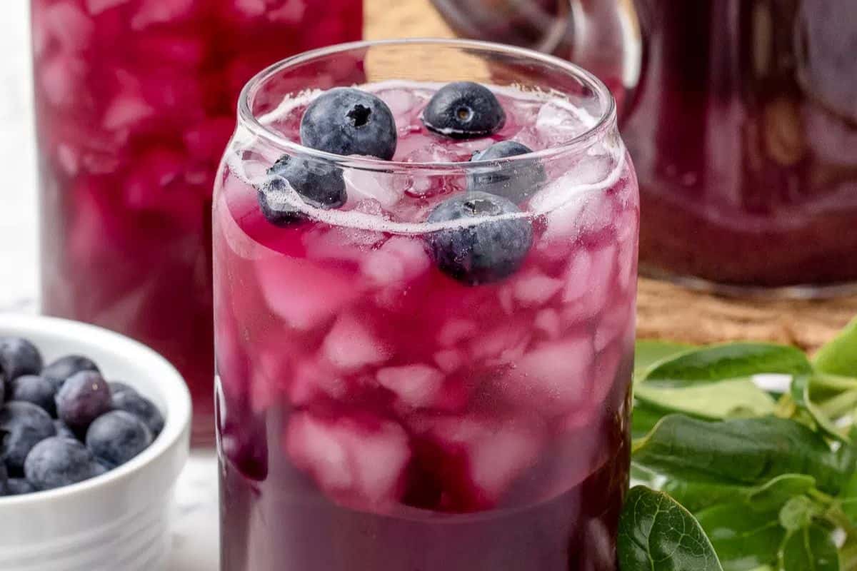 Close-up image of a glass of blueberry iced tea, garnished with blueberries.