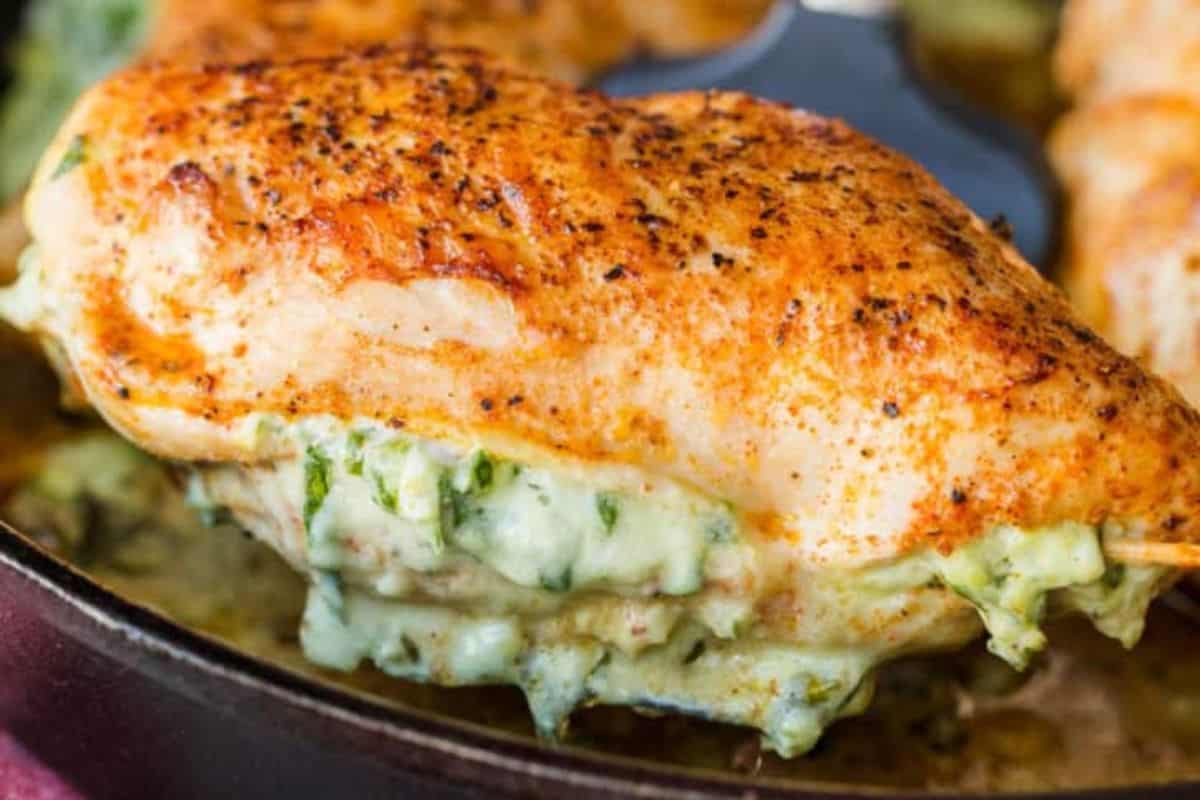 A cooked, seasoned chicken breast stuffed with a creamy spinach and cheese filling sits in a skillet—one of the best easy spinach recipes for picky eaters.