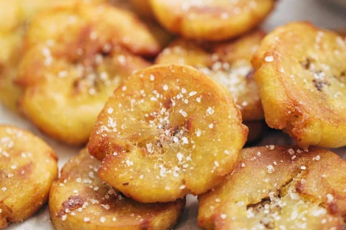 Close-up of several fried plantain slices sprinkled with coarse salt, a classic addition to Cuban dishes and perfect for spicing up your dinner.
