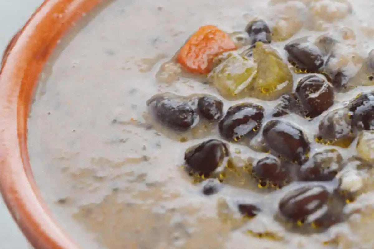 Close-up of a bowl of black bean soup, a classic among Cuban dishes, with visible black beans and vegetables in a thick, spice-infused broth—perfect for dinner.