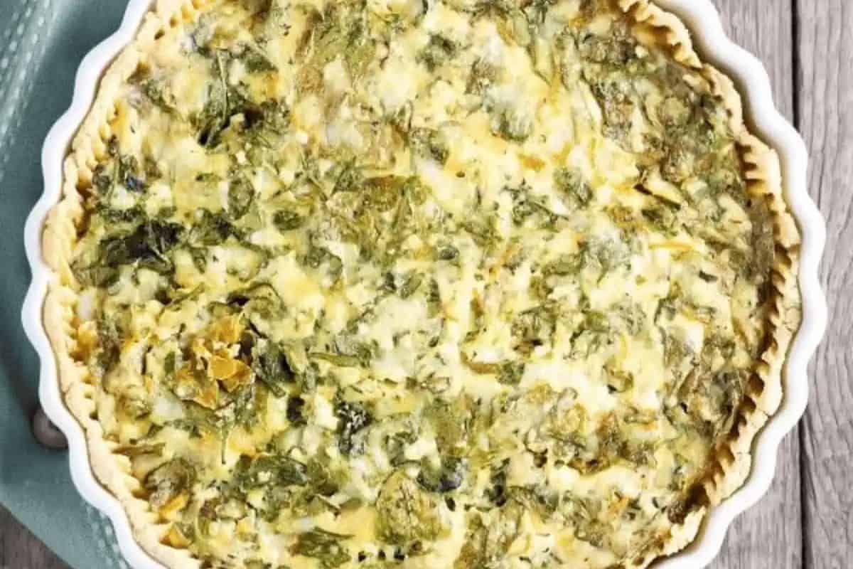 A baked spinach and cheese quiche in a round pie dish, viewed from above, with a golden-brown crust and a leafy green filling—one of the best easy spinach recipes perfect for picky eaters.