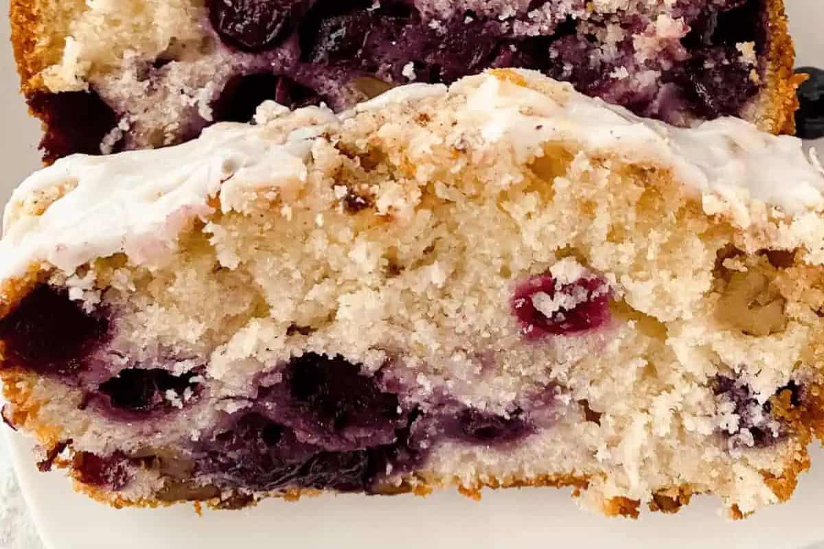 Close-up image of a slice of lemon bluberry loaf, served on a white plate.