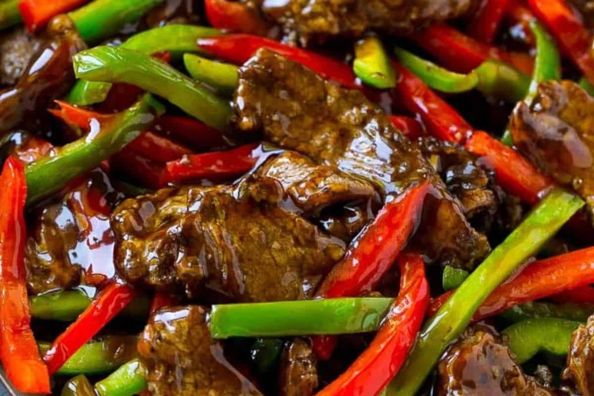 Close-up of a stiry fry with steak and red and green bell peppers, smothered in an asian stir fry sauce.
