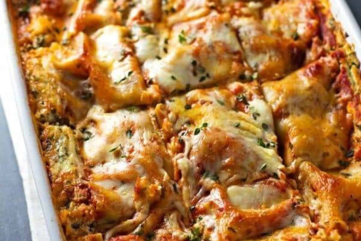 A close-up view of a baked lasagna in a rectangular dish, topped with melted cheese and sprinkled with herbs—an ideal choice for easy spinach recipes that even picky eaters will love.