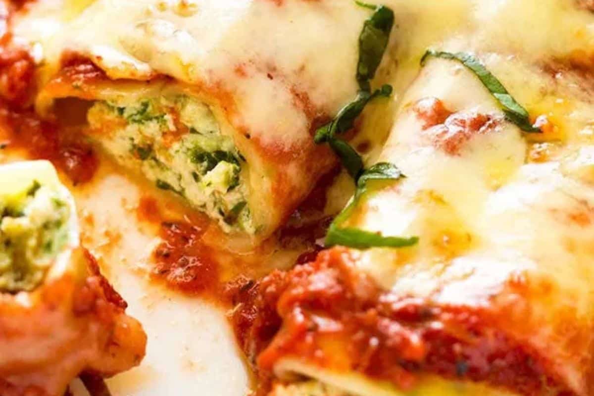 Close-up of cheesy baked lasagna roll-ups filled with ricotta and spinach, topped with tomato sauce and garnished with fresh basil—a perfect choice for easy spinach recipes even picky eaters will love.