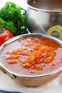 A metal bowl filled with stewed tomatoes.