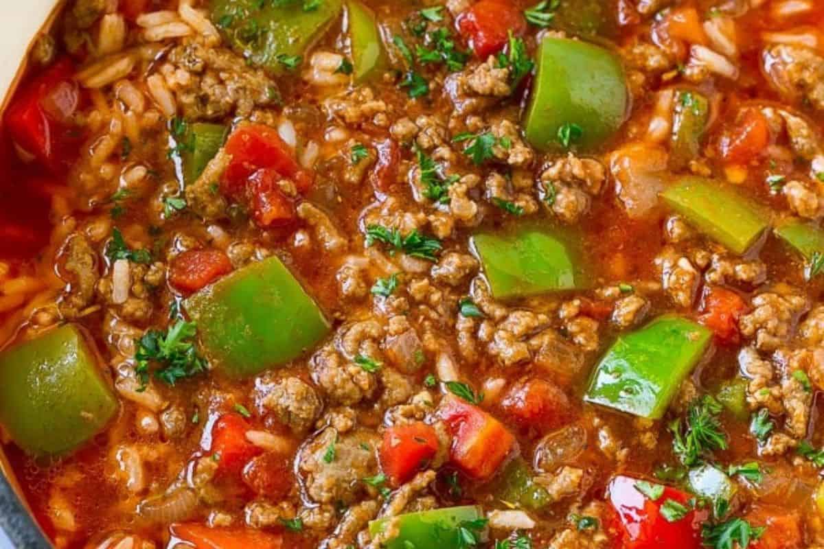 Close-up of soup with ground beef, rice, and red and green bell peppers.