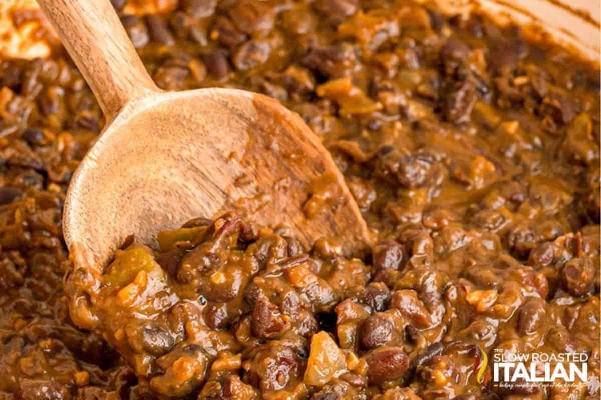 Close-up of black beans being scooped with a wooden spoon, showing their glossy texture and rich color.