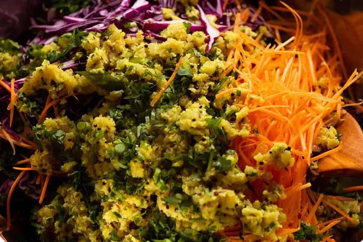 Close-up of shredded carrots, chopped green herbs, grated vegetables, and sliced purple cabbage in a bowl—perfect for adding bold flavors to Indian recipes.