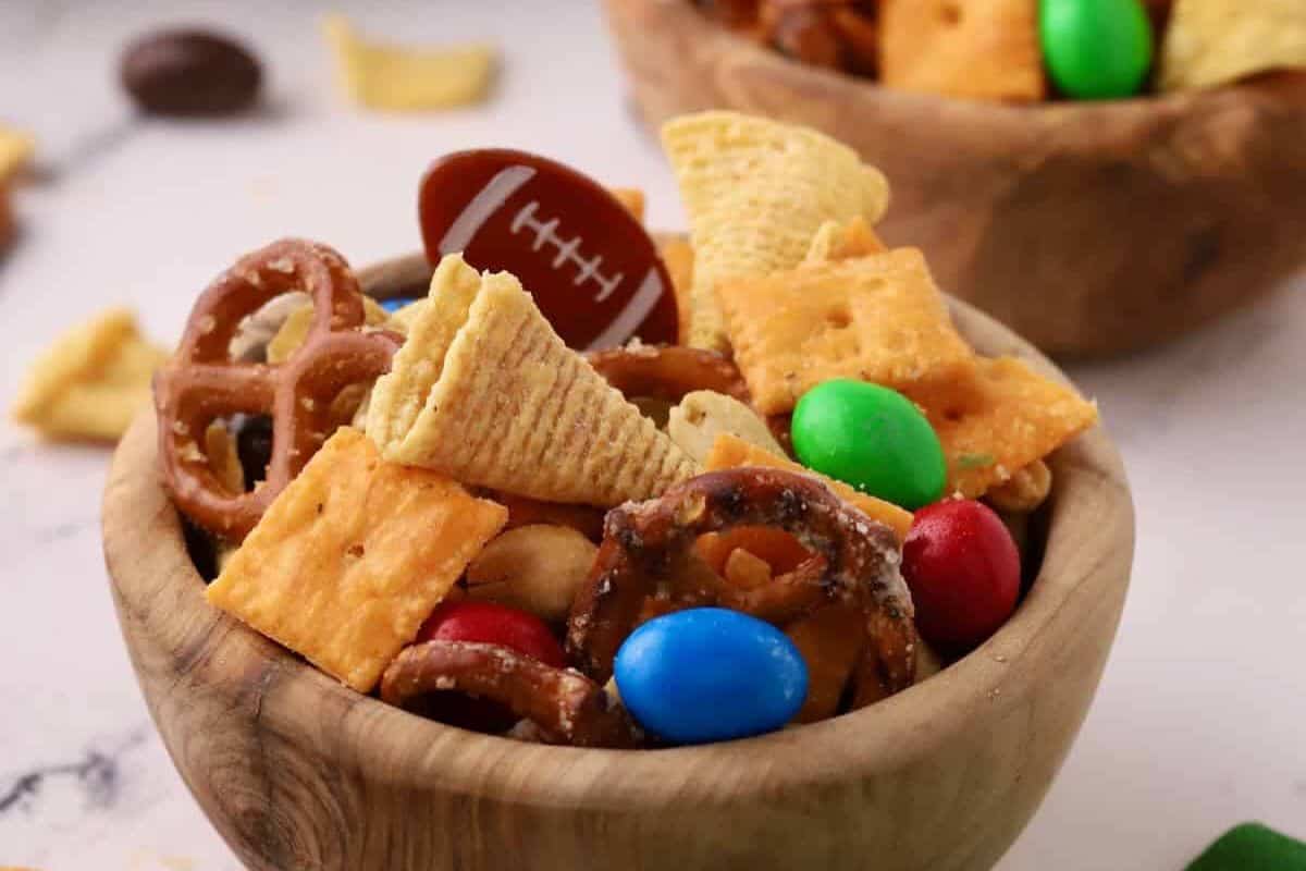 A colorful game day snack mix with M&Ms, pretzels, Bugles, Cheez-Its, and peanuts tossed together for a sweet and salty combination.