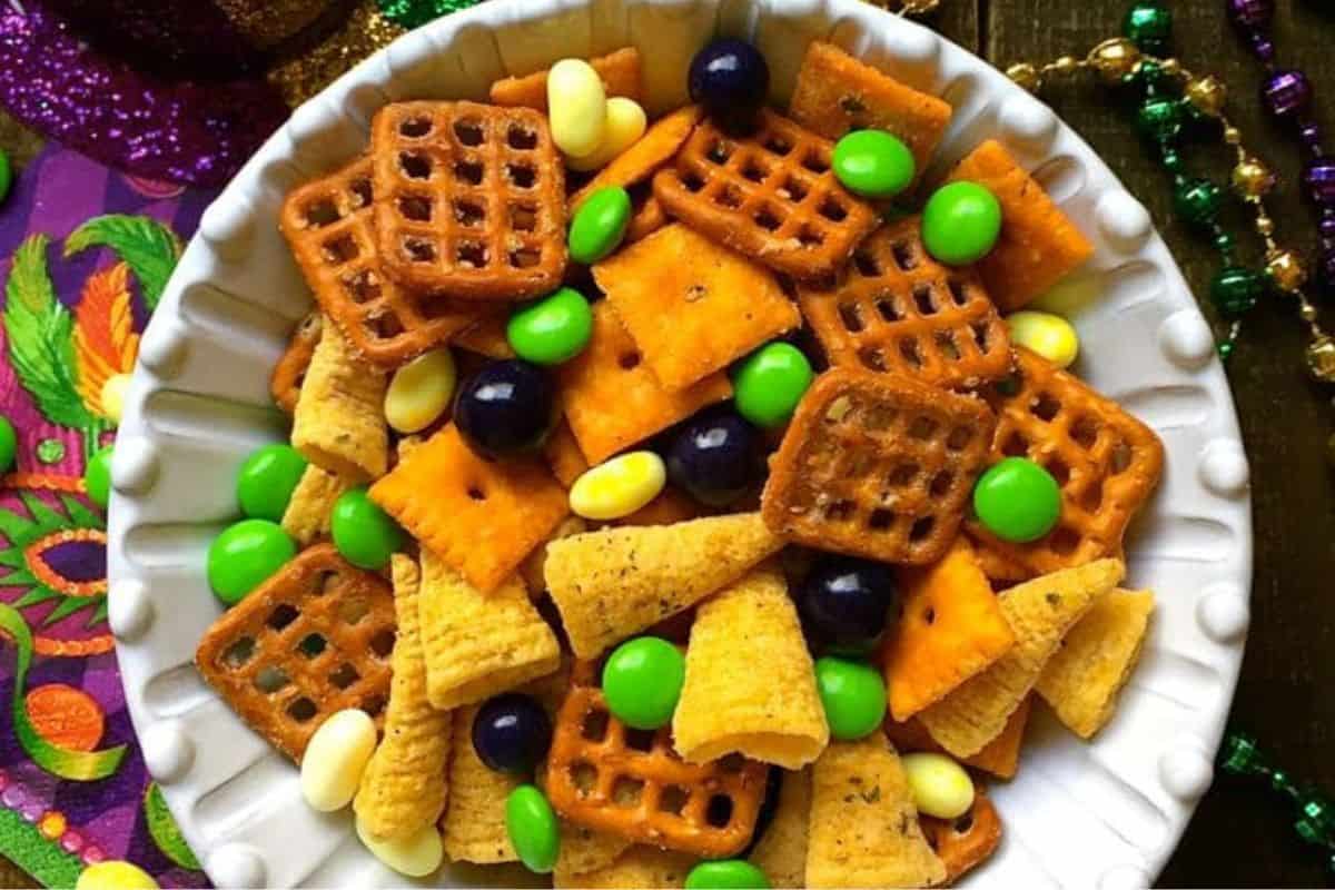 Festive Mardi Gras snack mix featuring popcorn, pretzels, and candies coated in purple, green, and gold sprinkles for a colorful celebration treat.