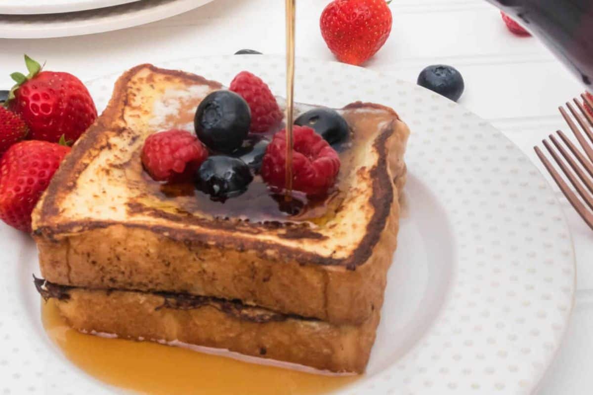 Thick slices of golden brown French toast topped with fresh mixed berries.