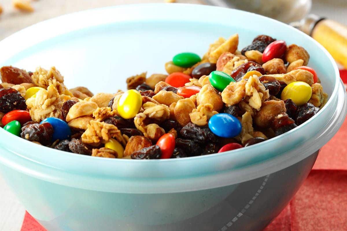 Hearty granola, dried fruit, and nuts in a blue bowl.