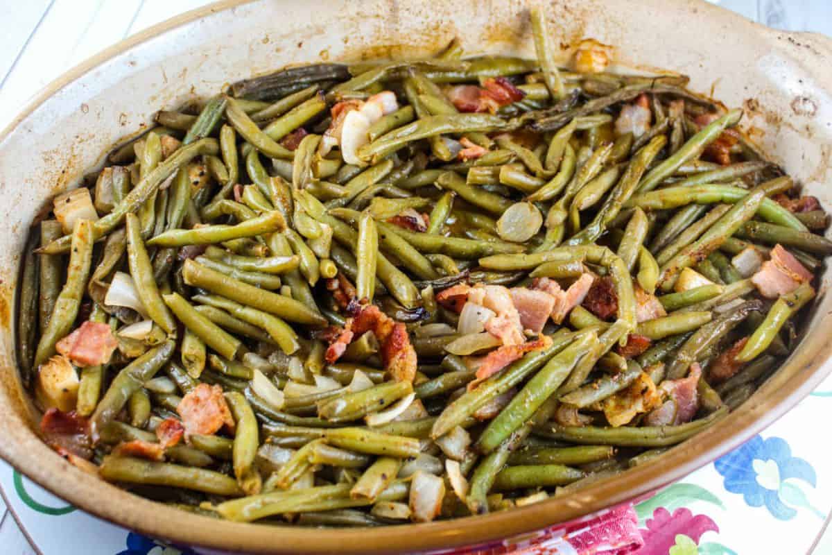 Smoked green beans mixed with crispy bacon bits, served in a rustic dish.