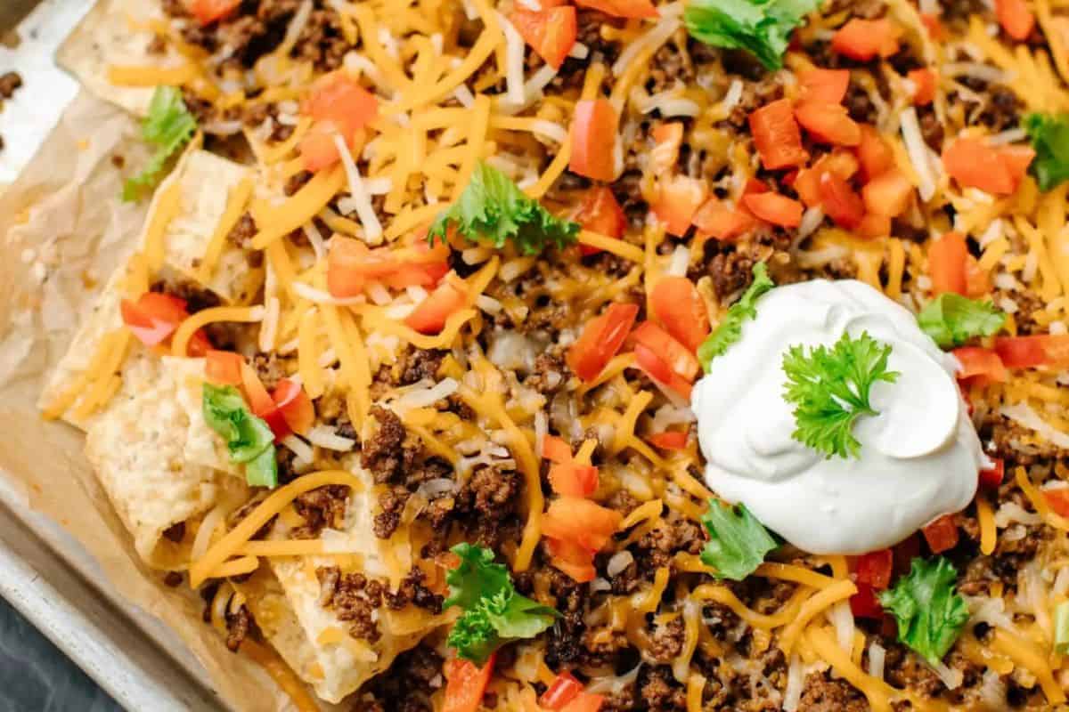 A plate of loaded nachos topped with melted cheese, sliced peppers, and diced tomatoes.