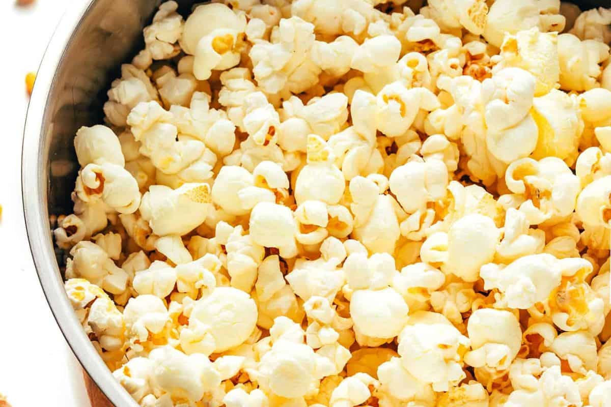 A close-up, overhead view of a metal bowl filled with fluffy, pale yellow popcorn.