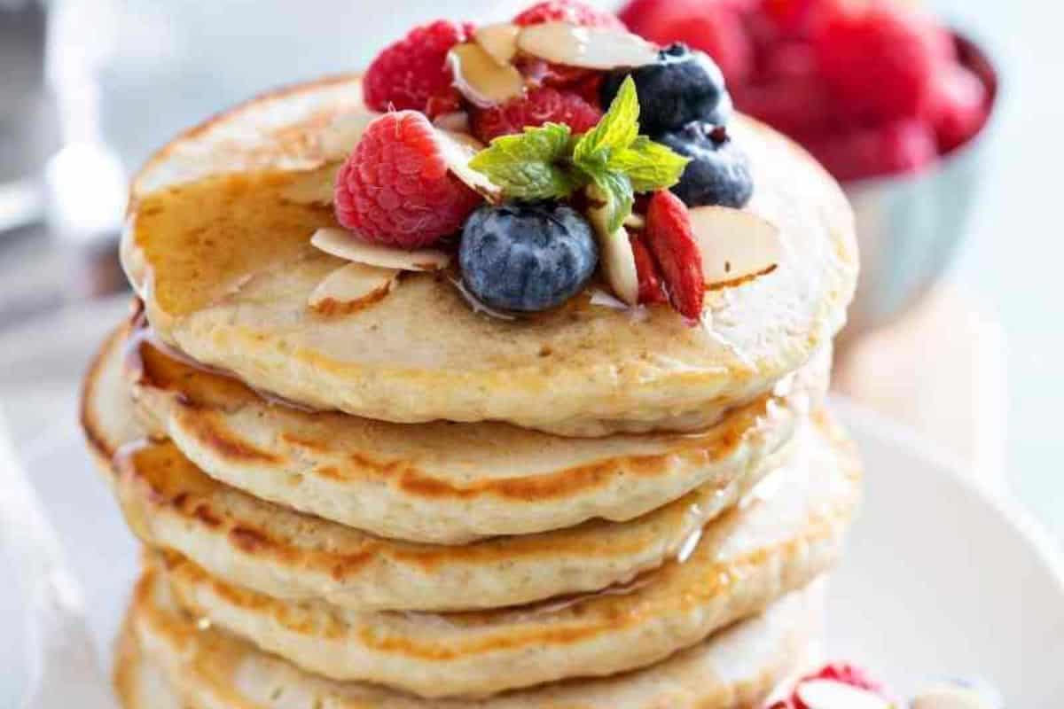 A stack of fluffy pancakes topped with fresh mixed berries and a drizzle of syrup.