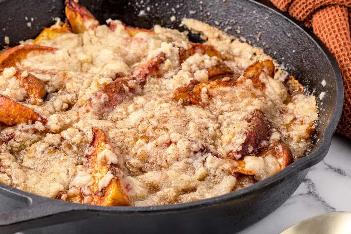 Warm smoked peach cobbler with golden-brown crust and juicy peach filling bubbling underneath.