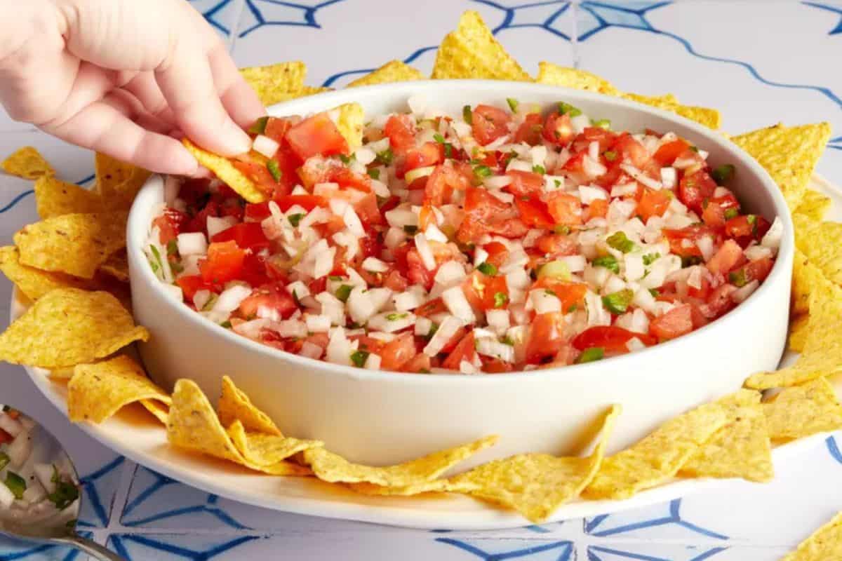 A colorful mix of diced fresh tomatoes, onions, jalapeños, cilantro, and lime juice, served as a fresh, chunky salsa in a bowl.