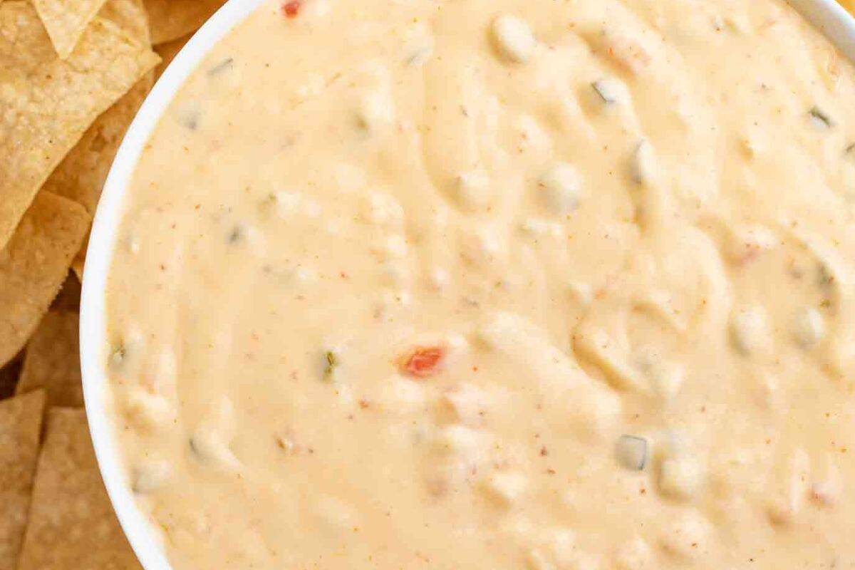 A bowl of smooth, melted queso cheese dip, creamy and rich, with a slightly golden color, perfect for dipping chips.