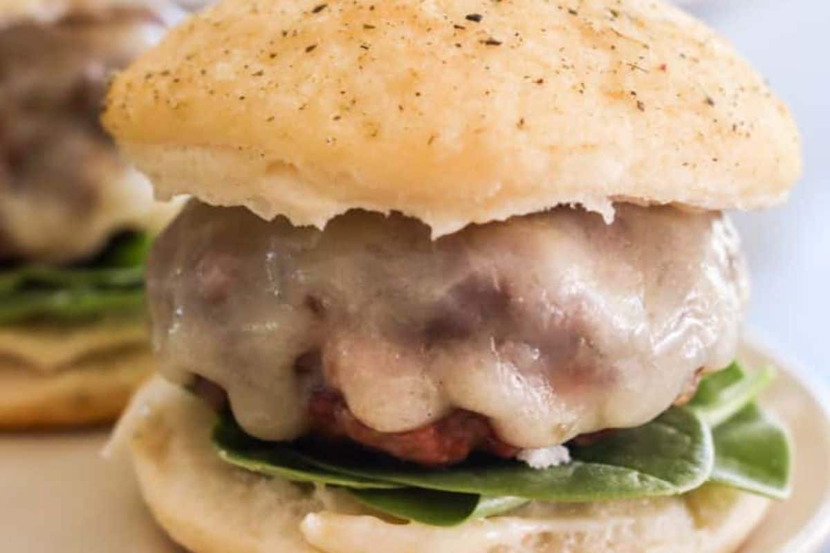 A close-up of a cheeseburger slider with melted cheese, spinach leaves, and a soft bun—perfect to upgrade your burger game.