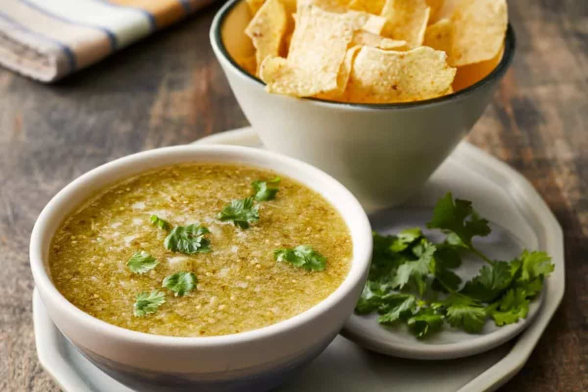 A bowl of bright green tomatillo salsa verde made with blended tomatillos, cilantro, jalapeños, onions, and lime juice, with a smooth and slightly chunky texture.