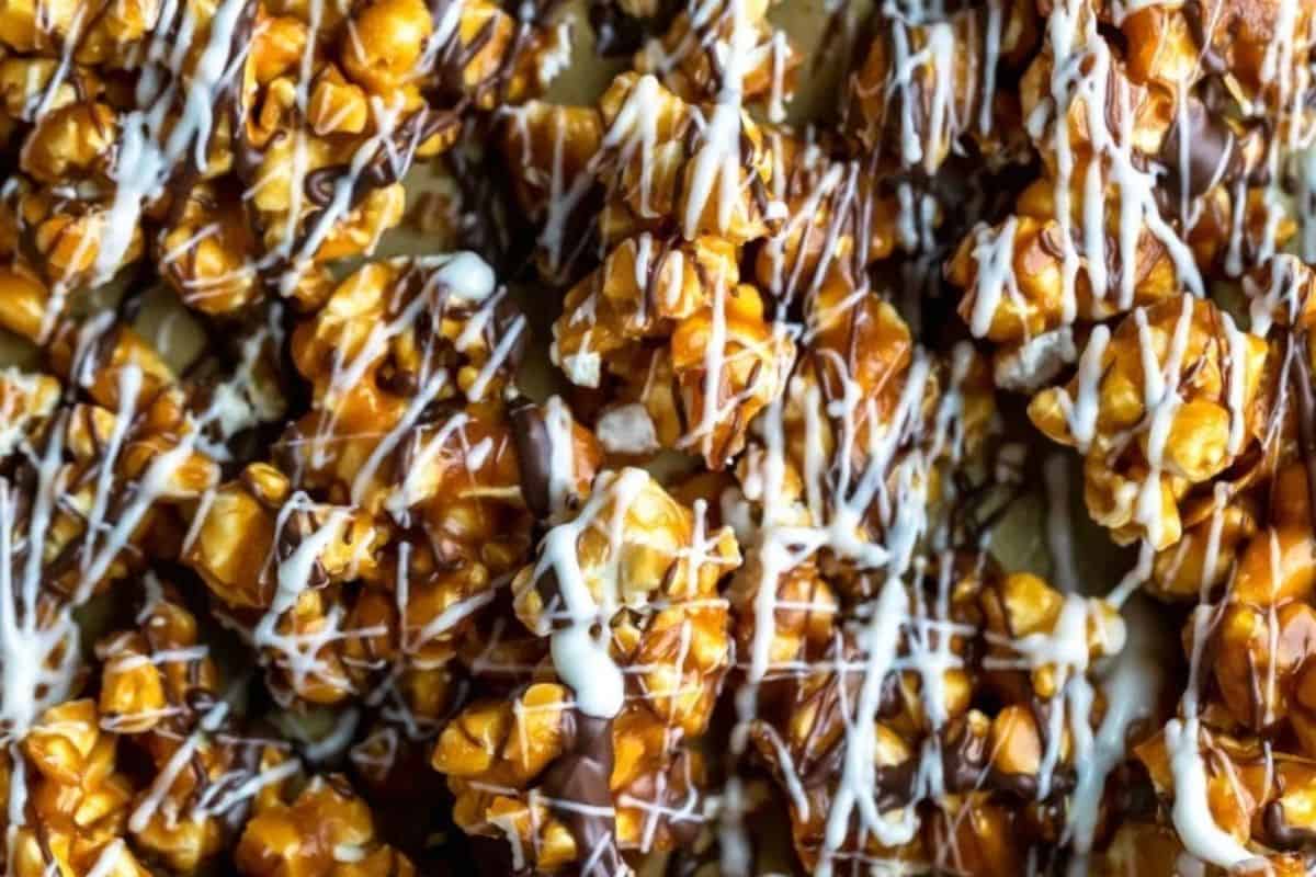 A close-up, overhead shot of caramel popcorn drizzled with both dark and white chocolate, creating a "zebra" stripe pattern.