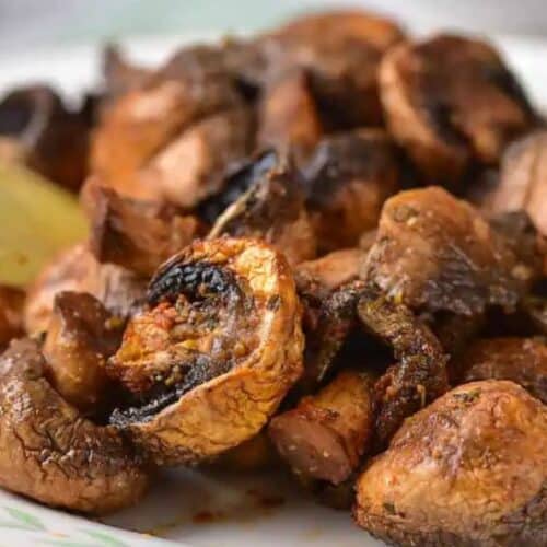 A plate of roasted mushrooms garnished with lemon wedges—one of those mushroom dishes you simply must try.