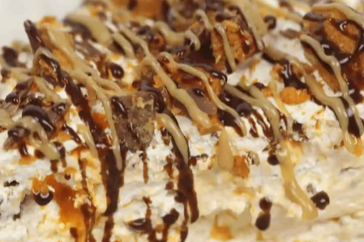 Close-up of a dessert topped with whipped cream, chocolate syrup, caramel drizzle, and small pieces of cookie or toffee—perfect inspiration for easy pie recipes or your favorite no bake pie recipes.