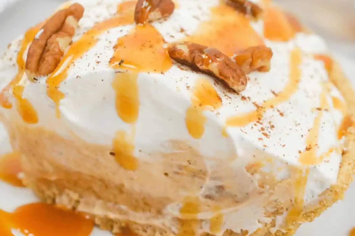 A slice of pie with a crumbly crust, creamy filling, whipped topping, pecan halves, and caramel sauce drizzled on top—perfect for fans of easy pie recipes.