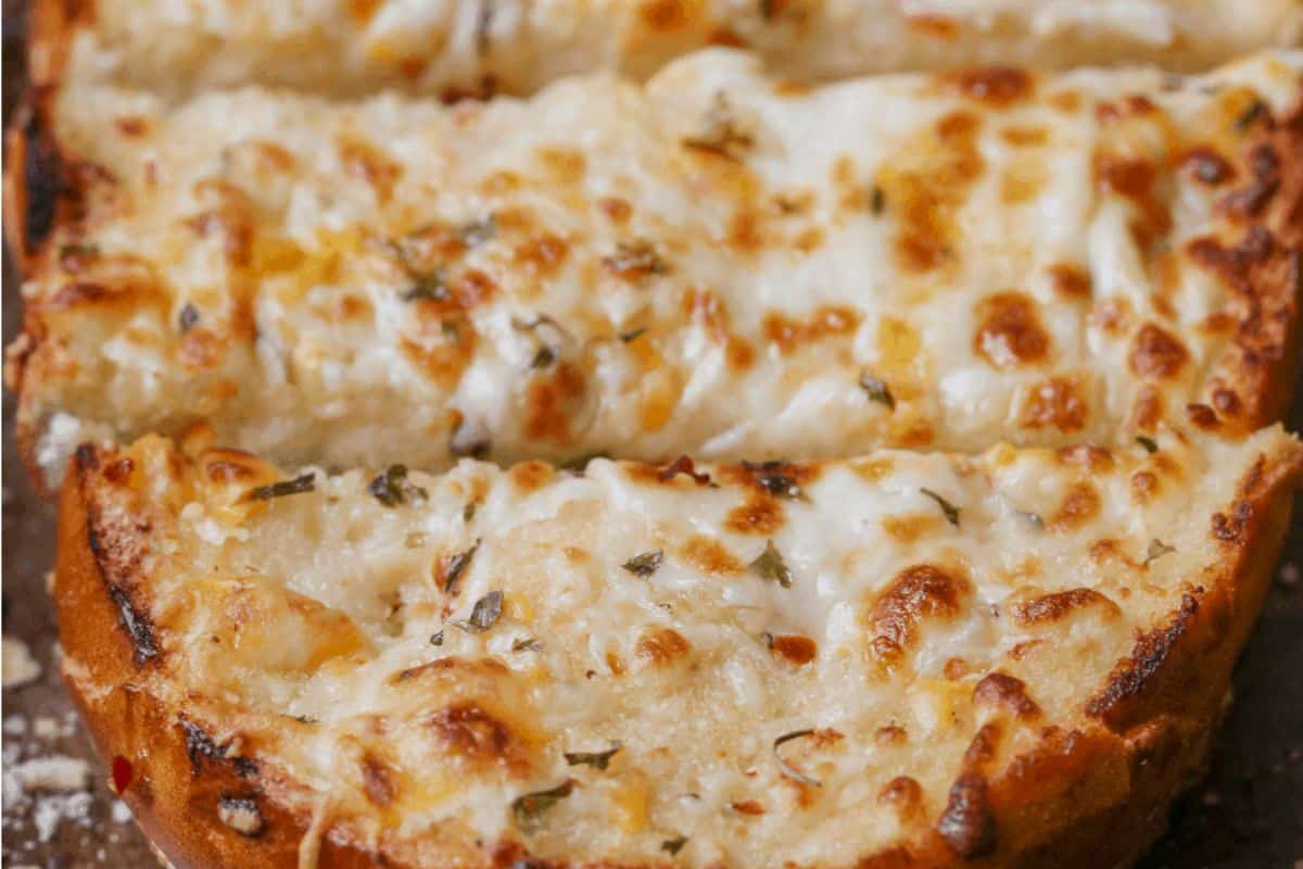 Close-up of some cheesy garlic bread, cut into dipping strips. 