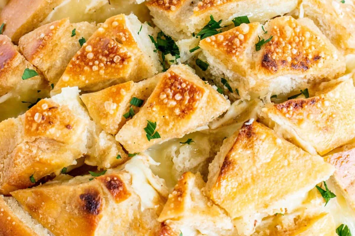 Close-up of some cheesy garlic stuffed pull apart bread, garnished with some green parsley.